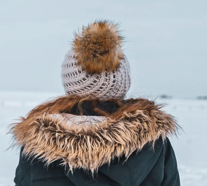 A picture of a person wearing a jacket with fur trim and a toque with a fur bauble.