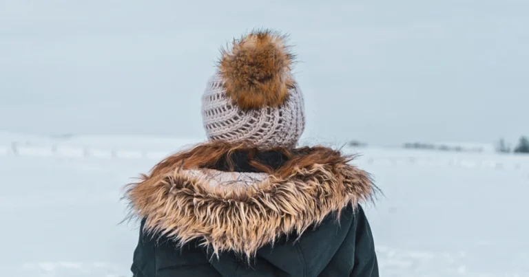A picture of a person wearing a jacket with fur trim and a toque with a fur bauble.
